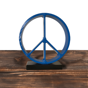 Blue metal peace sign sculpture on black base, sitting on wood surface