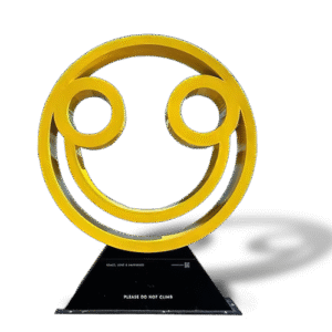 Large yellow smiley face sculpture with black base for outdoor art or public installations